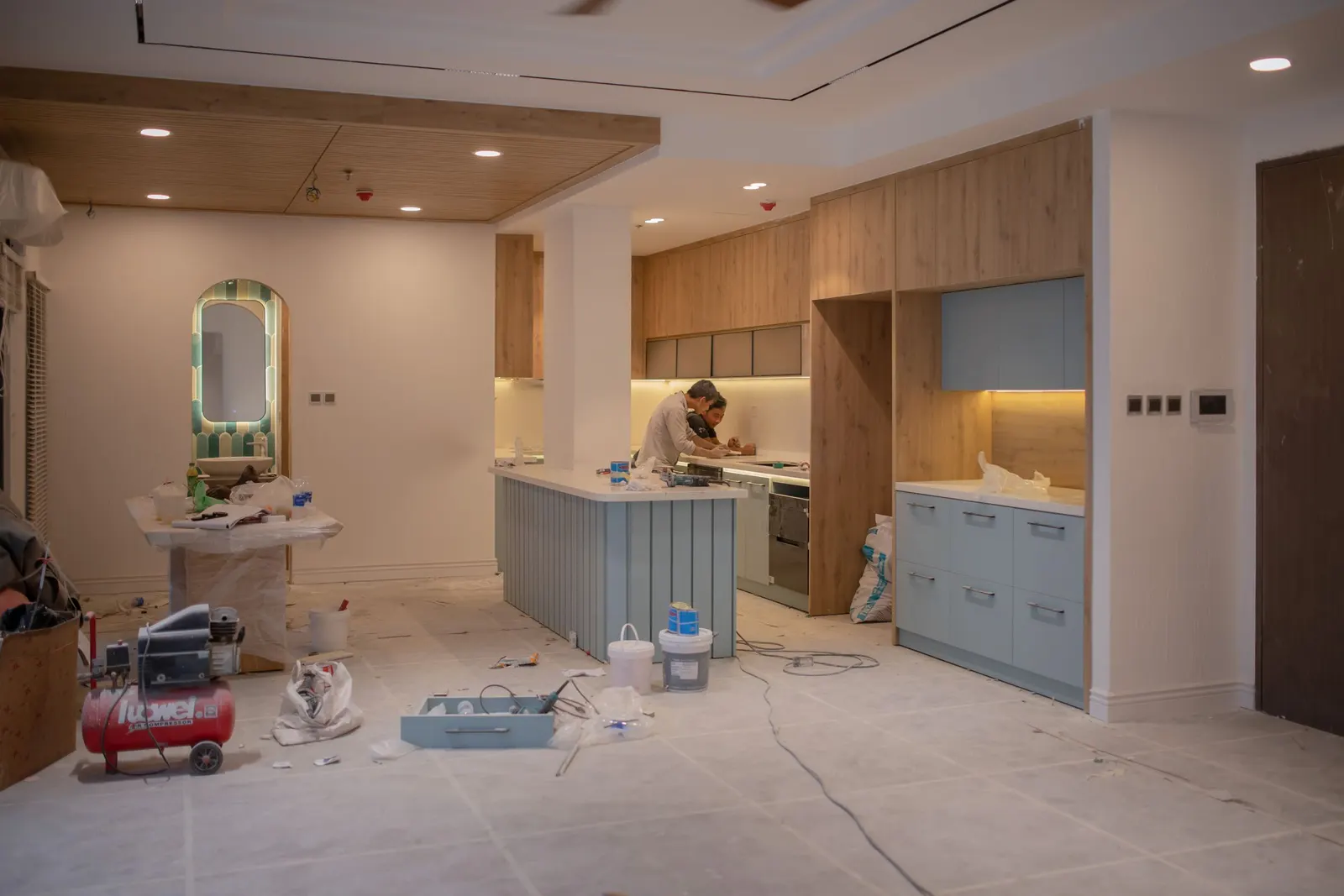 Apartment kitchen during installation, with modular units and an island in place and tools on the protected floor