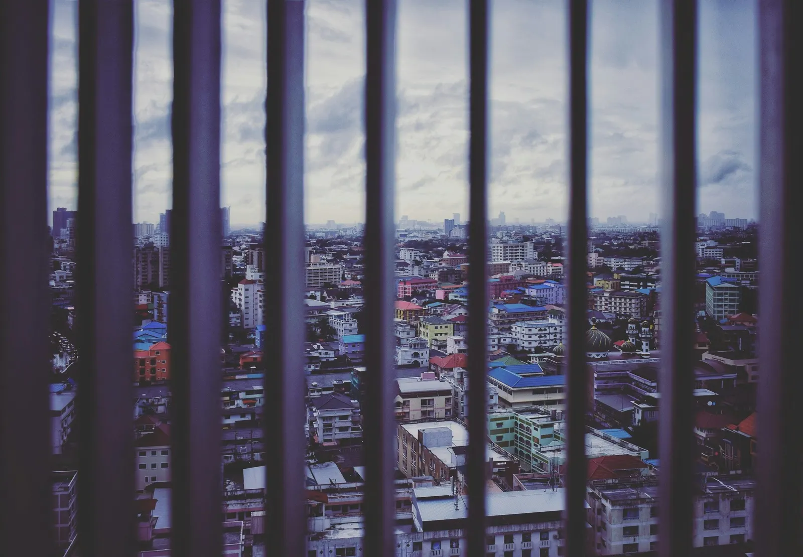 City view from a high floor seen through thick vertical window bars