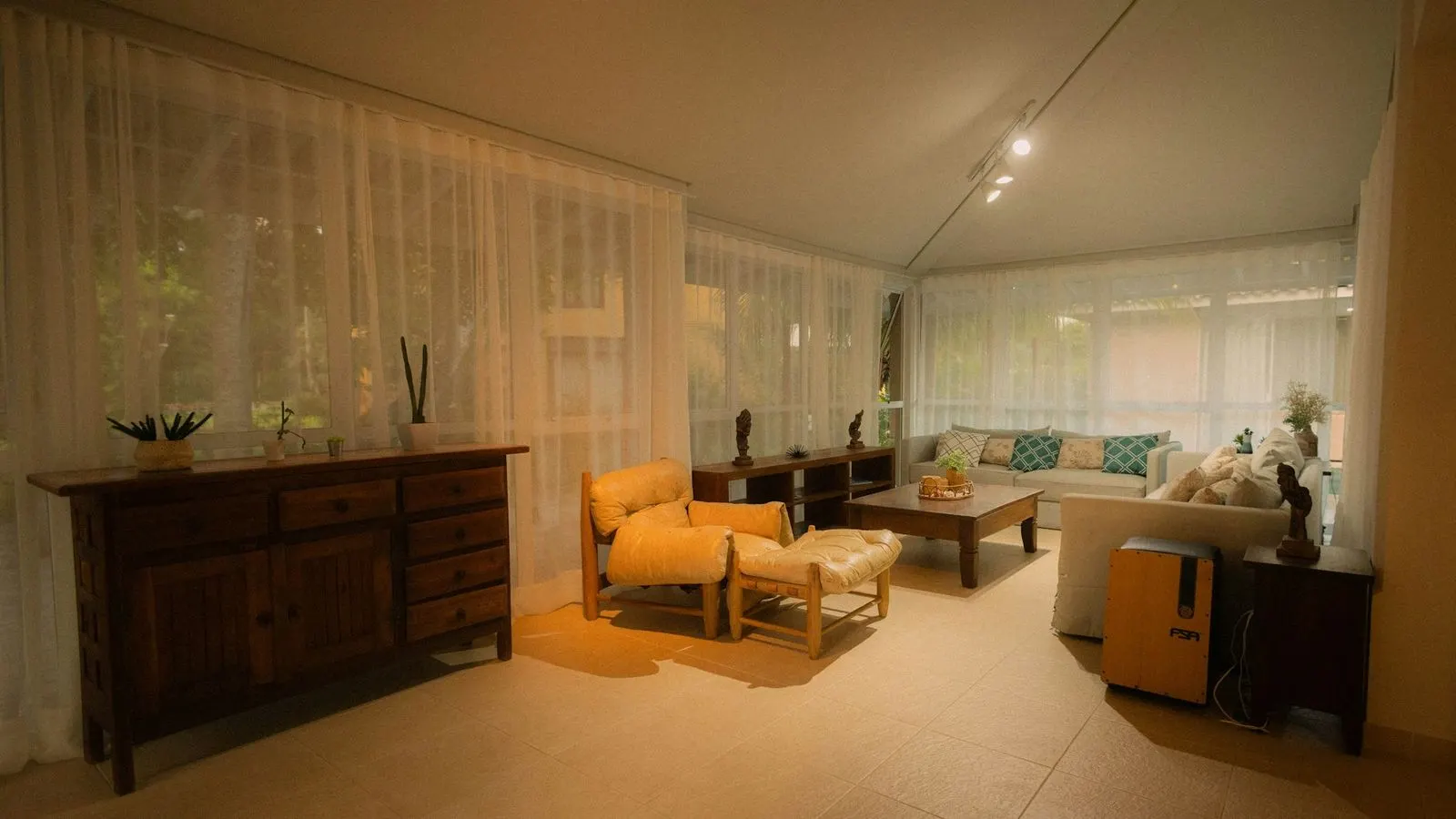 Living room in the evening with floor-to-ceiling sheer curtains drawn across a wall of windows