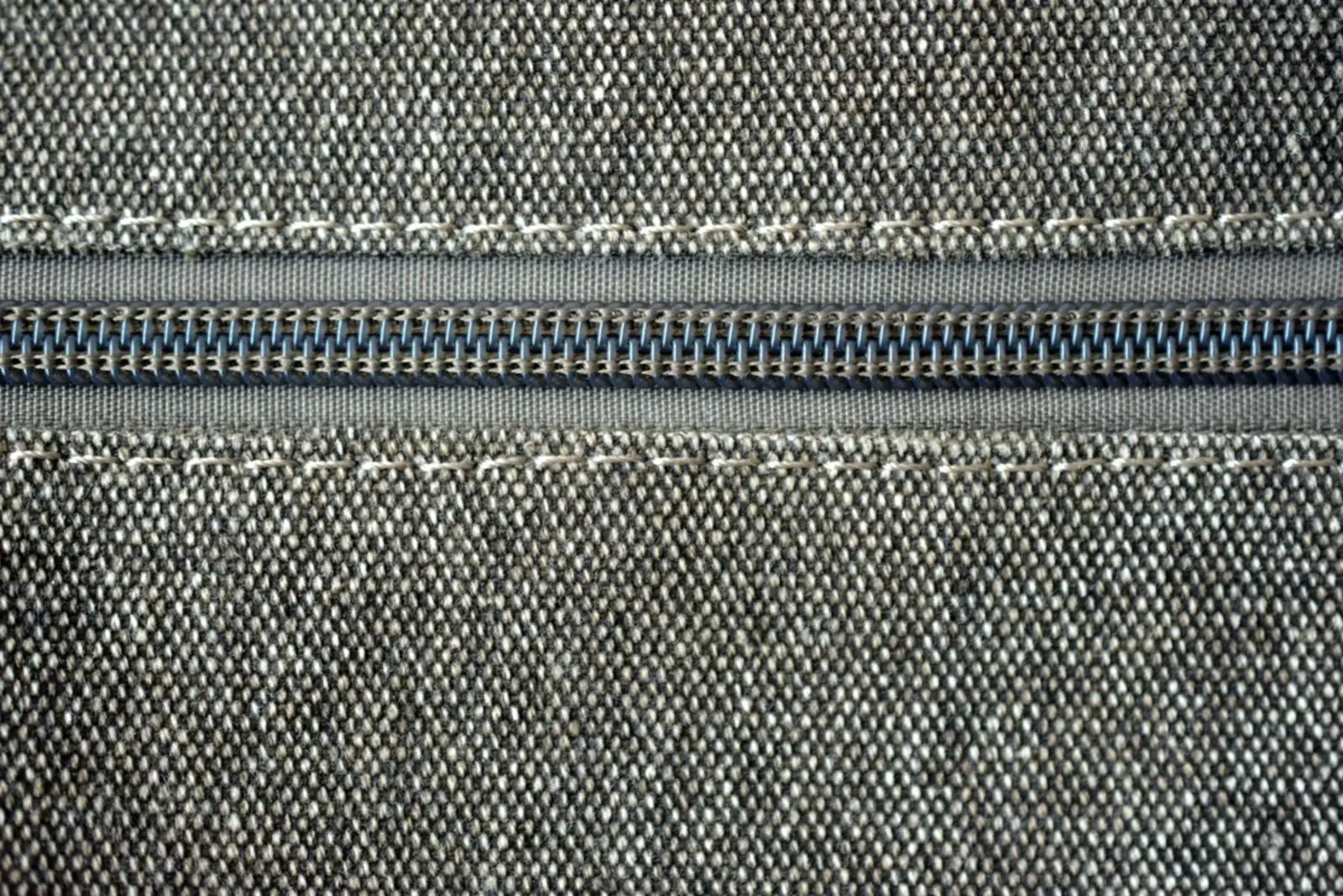 Close-up of a zip stitched into grey woven upholstery fabric with contrast topstitching