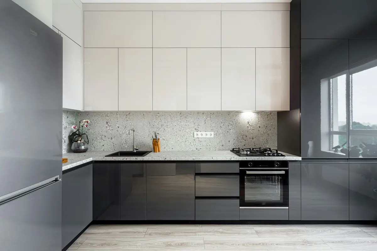 Kitchen with high-gloss grey base shutters, high-gloss white wall units, a terrazzo-look counter and a gas hob above a built-in oven