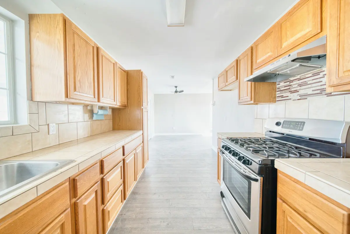 Parallel kitchen with two facing runs of oak cabinets, a sink on one side and a gas range on the other