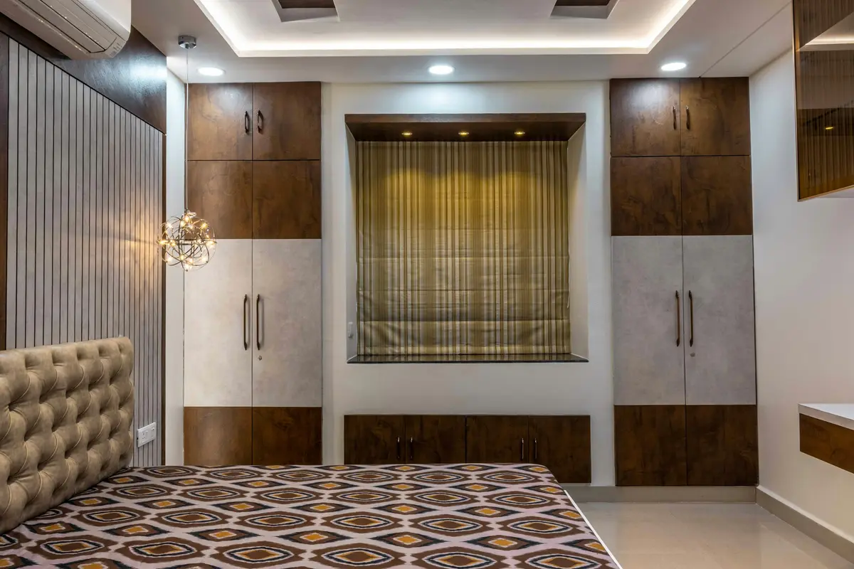 Bedroom with two tall walnut and stone-grey wardrobes either side of a window, each with a separate loft cabinet above the main doors